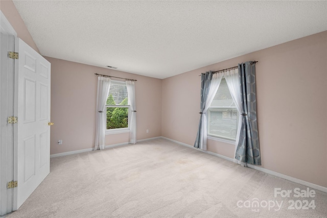 carpeted empty room with a textured ceiling