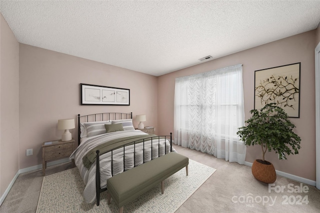 bedroom featuring light carpet and a textured ceiling