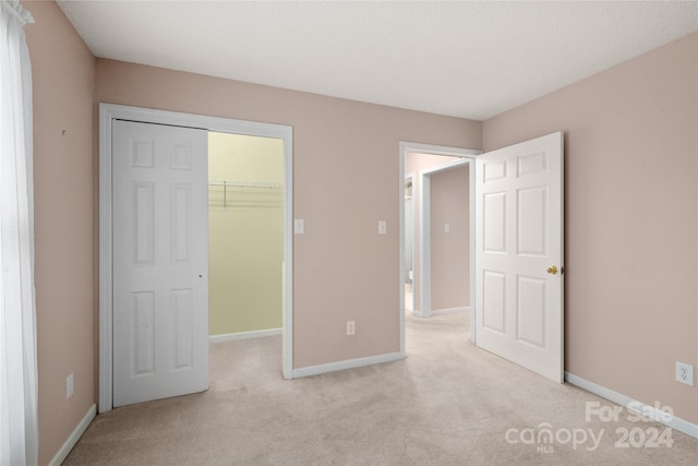 unfurnished bedroom featuring light colored carpet, a closet, and a walk in closet