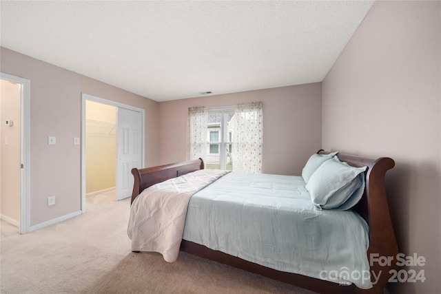 carpeted bedroom with a textured ceiling, a closet, and a walk in closet