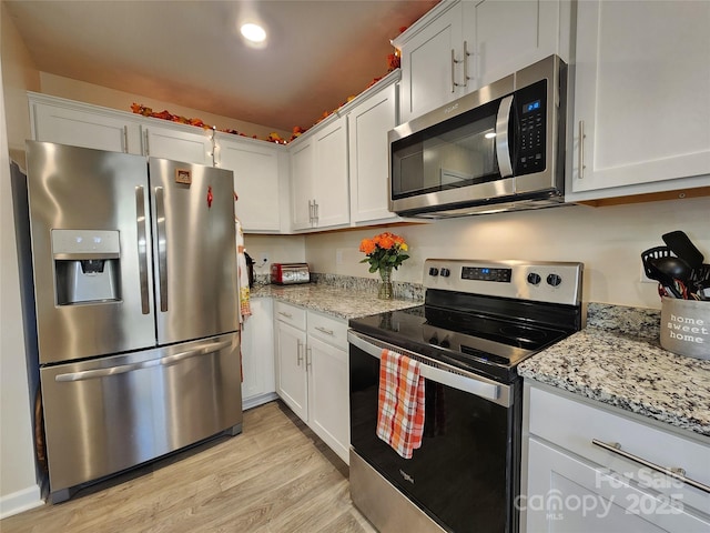 kitchen with stainless steel appliances, light stone countertops, light hardwood / wood-style floors, and white cabinetry