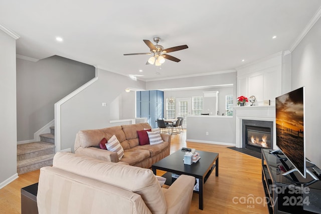 living room featuring ornamental molding, light hardwood / wood-style flooring, a fireplace, and ceiling fan