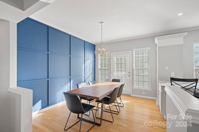 dining room with crown molding, an inviting chandelier, and light wood-type flooring