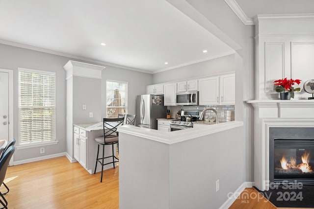 kitchen featuring appliances with stainless steel finishes, a wealth of natural light, kitchen peninsula, and a breakfast bar area