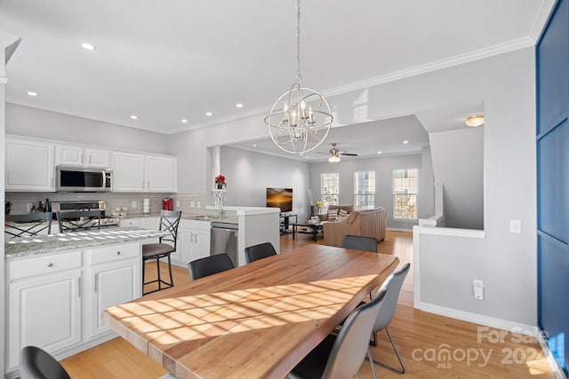 dining room with light hardwood / wood-style flooring, ornamental molding, and ceiling fan with notable chandelier