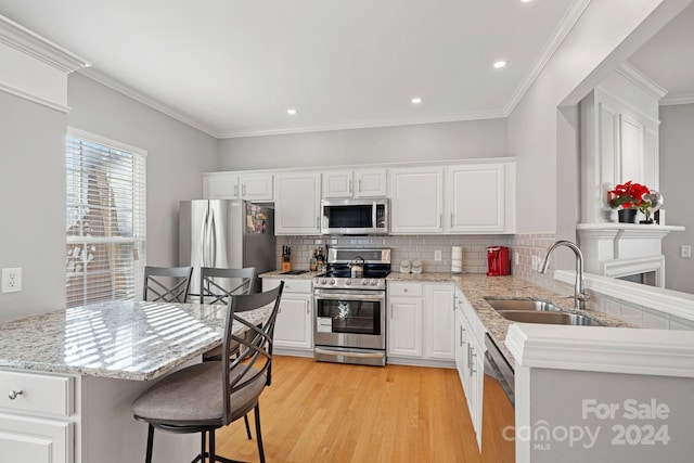 kitchen featuring sink, stainless steel appliances, white cabinets, ornamental molding, and light hardwood / wood-style flooring