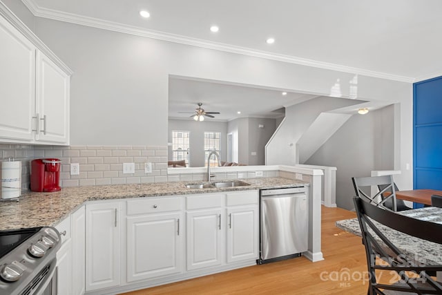 kitchen with decorative backsplash, appliances with stainless steel finishes, white cabinetry, light hardwood / wood-style floors, and sink