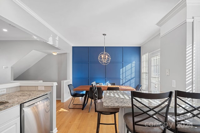 dining area featuring light hardwood / wood-style flooring, a notable chandelier, and crown molding