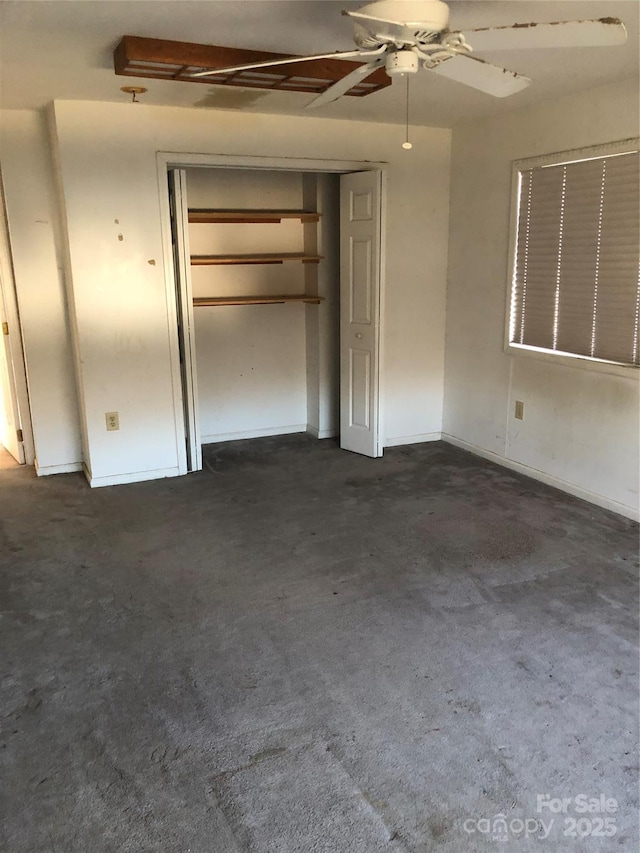 unfurnished bedroom with dark colored carpet, ceiling fan, and a closet