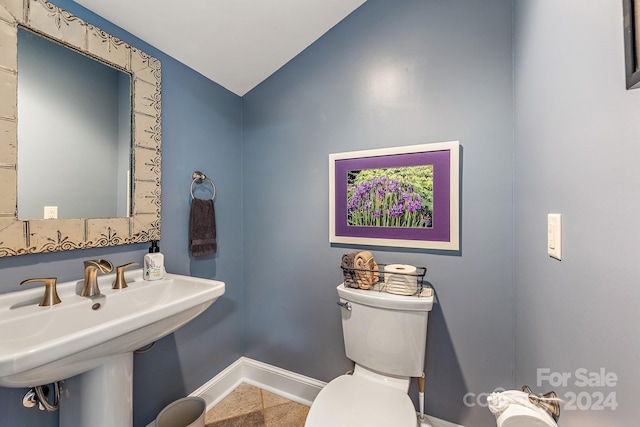 bathroom featuring toilet, lofted ceiling, and sink