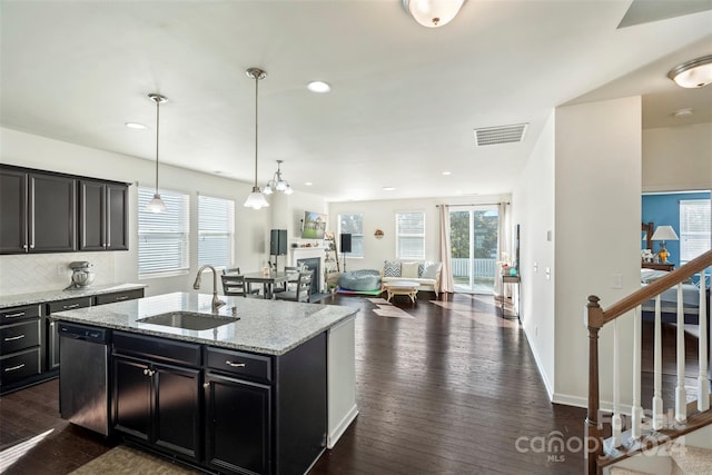 kitchen featuring decorative backsplash, hanging light fixtures, dark hardwood / wood-style flooring, dishwasher, and sink