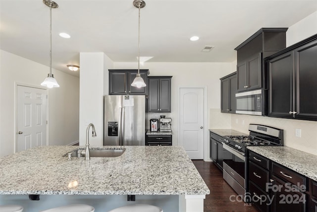 kitchen with sink, a breakfast bar, appliances with stainless steel finishes, and pendant lighting