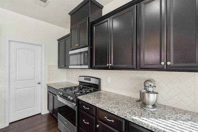 kitchen featuring appliances with stainless steel finishes, tasteful backsplash, light stone counters, and dark hardwood / wood-style flooring