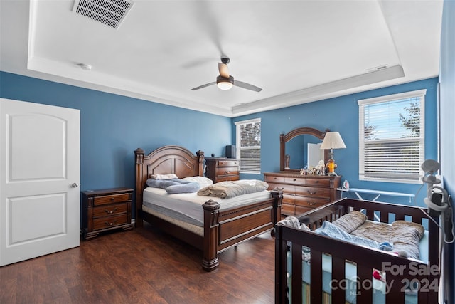 bedroom featuring dark wood-type flooring, ceiling fan, and a tray ceiling