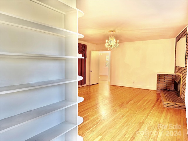 unfurnished living room featuring hardwood / wood-style flooring, a notable chandelier, and a fireplace