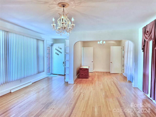 spare room with light wood-type flooring, a baseboard radiator, and an inviting chandelier