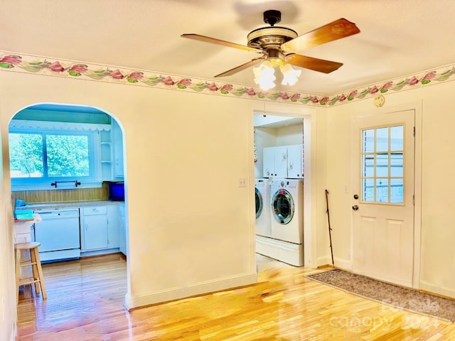 laundry area with washing machine and clothes dryer, ceiling fan, light hardwood / wood-style flooring, and cabinets