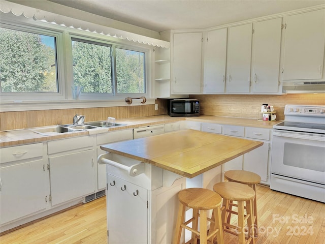 kitchen featuring white cabinetry, a kitchen breakfast bar, white range with electric stovetop, extractor fan, and a kitchen island