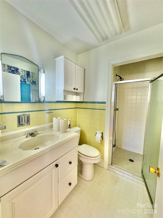 bathroom with toilet, vanity, tile walls, and walk in shower