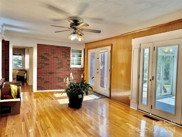 interior space featuring french doors, brick wall, a textured ceiling, ceiling fan, and light hardwood / wood-style flooring