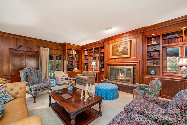 carpeted living room with wooden walls, crown molding, a brick fireplace, and built in shelves