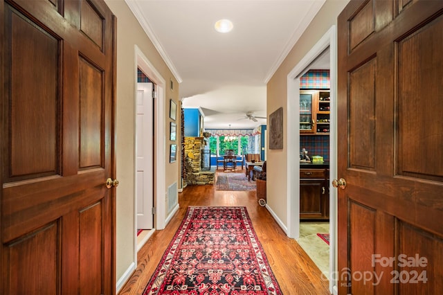 hallway with light hardwood / wood-style floors and crown molding