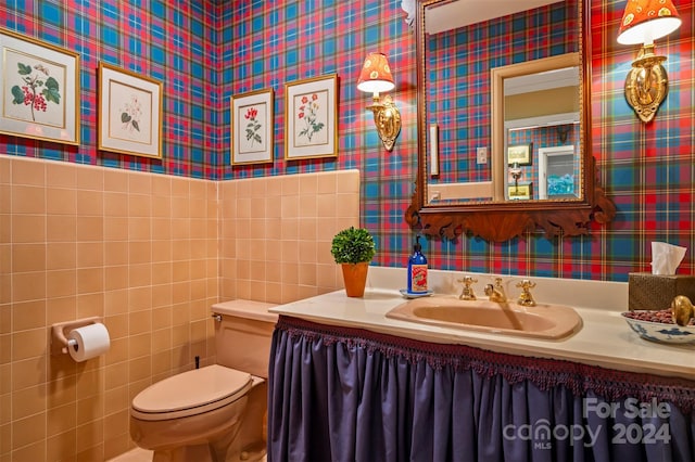 bathroom with vanity, toilet, and tile walls