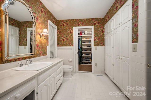 bathroom featuring vanity, toilet, tile patterned floors, and tile walls