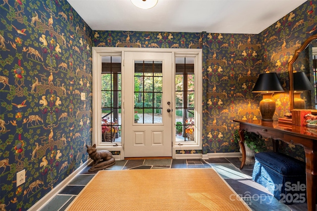 foyer entrance featuring wallpapered walls and baseboards