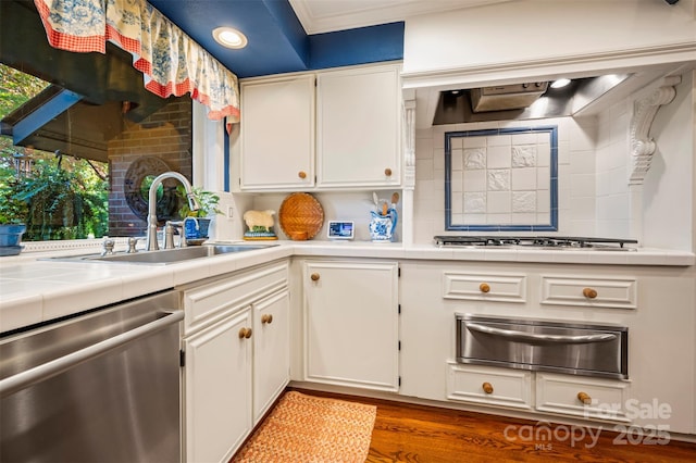 kitchen featuring a warming drawer, a sink, tile countertops, appliances with stainless steel finishes, and white cabinets