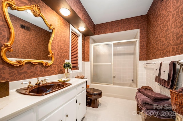 bathroom with vanity, visible vents, wallpapered walls, wainscoting, and tile walls