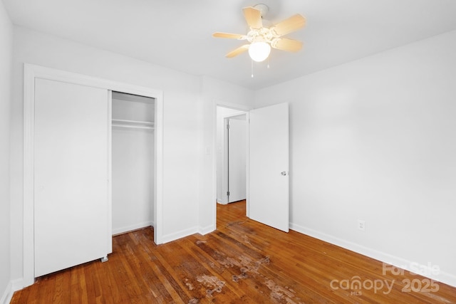 unfurnished bedroom featuring dark hardwood / wood-style flooring, ceiling fan, and a closet