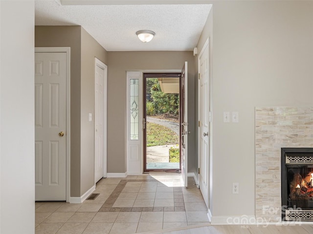 entrance foyer with light tile patterned floors, a textured ceiling, visible vents, baseboards, and a tile fireplace