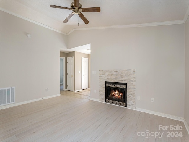 unfurnished living room with a tiled fireplace, ceiling fan, lofted ceiling, ornamental molding, and light hardwood / wood-style flooring