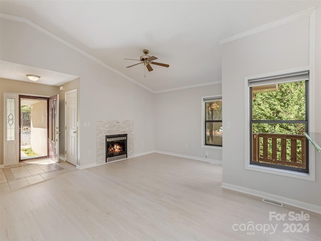 unfurnished living room featuring light hardwood / wood-style floors, a stone fireplace, vaulted ceiling, and ceiling fan