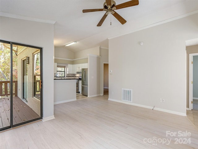 unfurnished living room with ceiling fan, ornamental molding, vaulted ceiling, and light wood-type flooring