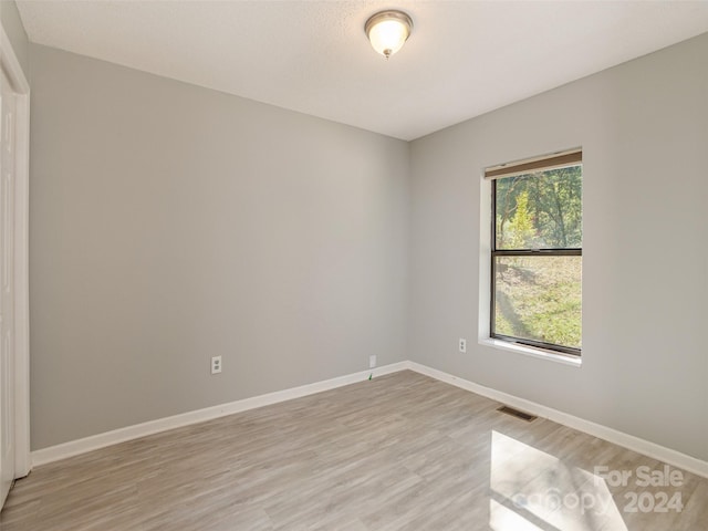 spare room featuring visible vents, light wood-style flooring, and baseboards