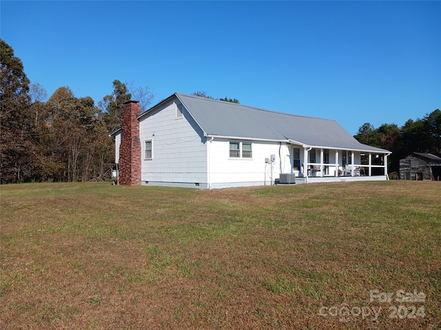 back of house with central AC, a yard, and covered porch