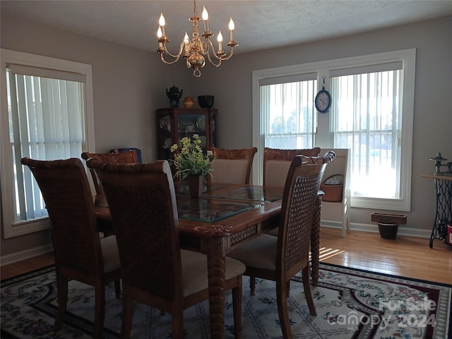 dining space featuring hardwood / wood-style flooring, a textured ceiling, and an inviting chandelier