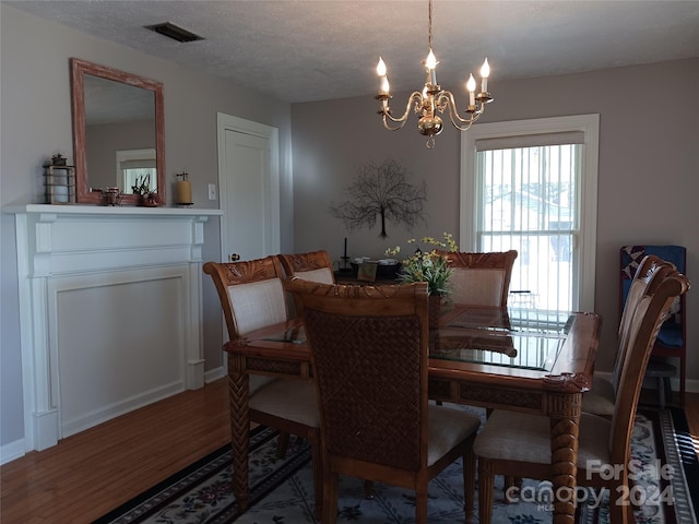 dining space with a chandelier, a textured ceiling, and hardwood / wood-style flooring