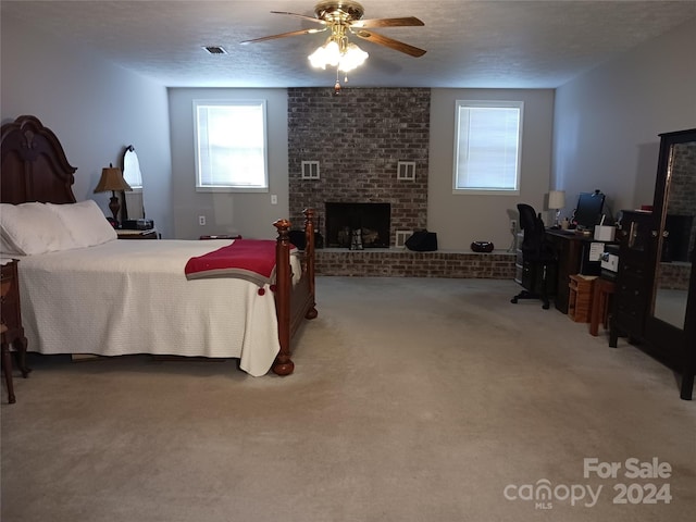 bedroom with a fireplace, a textured ceiling, carpet floors, and ceiling fan