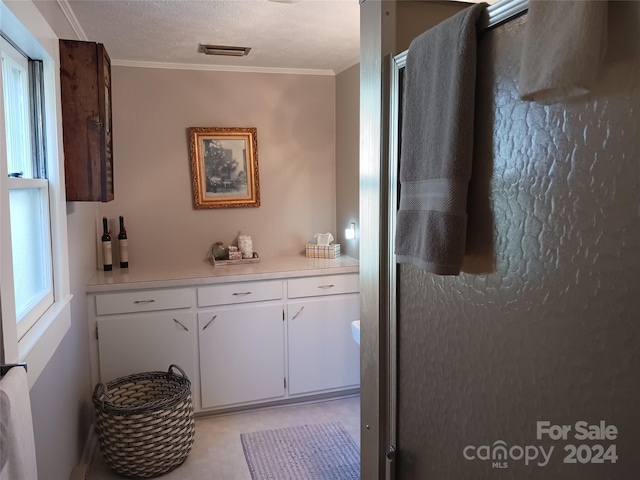 bathroom featuring crown molding, vanity, a textured ceiling, and walk in shower