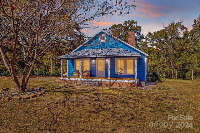 exterior space with covered porch and a yard