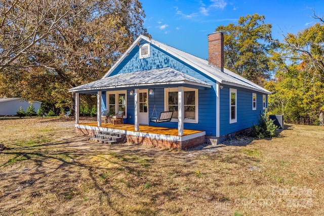 view of front of house with central AC, covered porch, and a front lawn