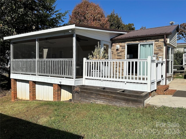 back of house featuring a sunroom, a yard, ceiling fan, and a deck