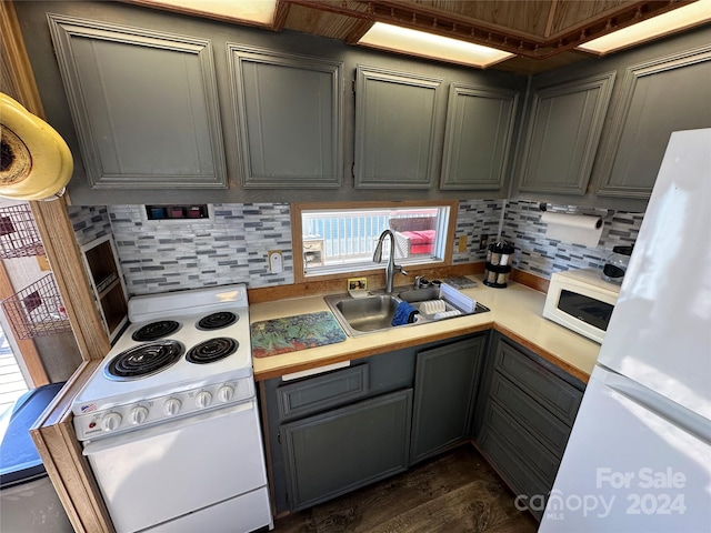 kitchen with dark wood-type flooring, white appliances, sink, and decorative backsplash