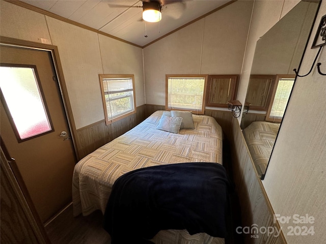 bedroom featuring wooden walls, ceiling fan, crown molding, and vaulted ceiling