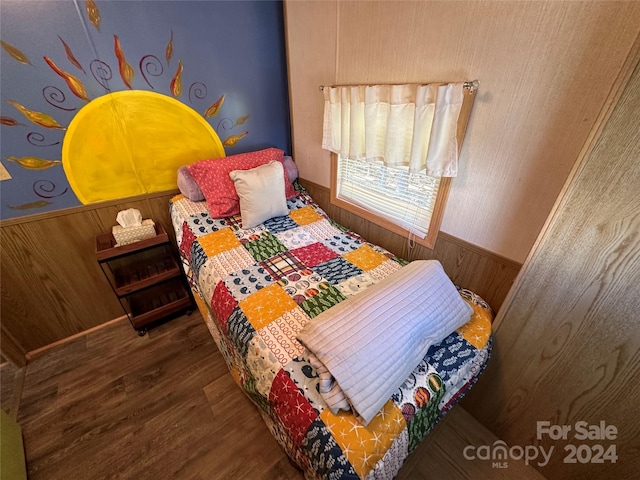 bedroom with wooden walls and dark hardwood / wood-style flooring