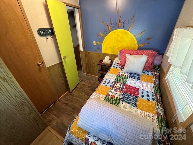 bedroom with wooden walls, dark hardwood / wood-style floors, and a closet