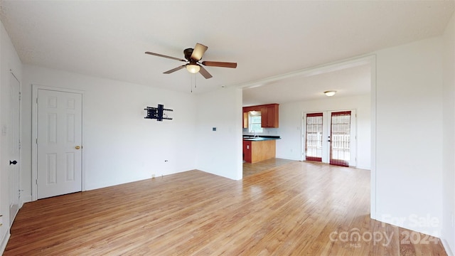 unfurnished living room with sink, ceiling fan, and light hardwood / wood-style flooring